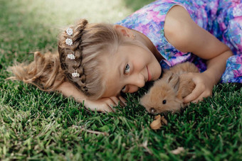女孩坐着绿色草兔子可爱的孩子女孩持有兔子手复活节一天