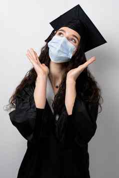 惊讶本科女孩医疗面具冠状病毒科维德期主毕业袍帽白色背景距离学习在线研究首页毕业大学