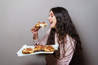 <strong>女孩快递</strong>吃平萨披萨罗马美食意大利厨房灰色背景持有scrocchiarella传统的菜食物交付比萨 店平萨肉芝麻菜橄榄奶酪