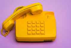 黄色的固定电话电话紫色的背景关闭