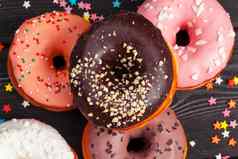 分类色彩斑斓的甜甜圈装饰色彩斑斓的五彩纸屑洒黑暗木背景