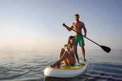 夫妇游客年轻的男人。女人有趣的paddleboarding海