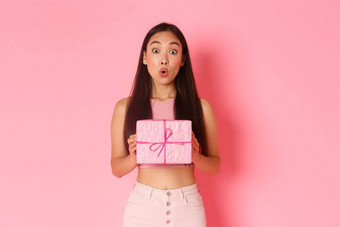假期庆祝活动生活方式概念惊讶感兴趣亚洲女孩庆祝生日收到包装礼物内部现在站逗乐粉红色的背景