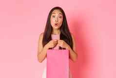 美时尚生活方式概念华丽的快乐亚洲女孩收到礼物持有购物袋微笑梦幻感激站粉红色的背景