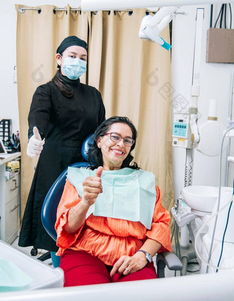 牙医拇指病人办公室女人显示拇指坐着牙医办公室牙医满意病人拇指