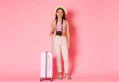 旅游夏天假期假期在国外概念完整的长度美丽的微笑女孩旅行者他旅游相机手提箱准备好了冒险站粉红色的背景