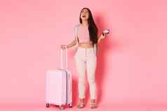 旅行假期假期概念全身的哭伤心陷入困境的亚洲女孩旅游感觉抑郁错过了飞行站手提箱飞机票粉红色的背景
