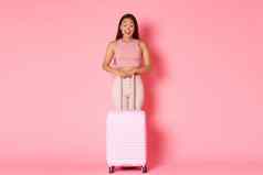 旅行假期假期概念全身的兴奋深刻的印象亚洲有吸引力的女孩惊讶快乐微笑站手提箱粉红色的背景