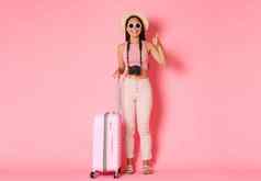 旅游夏天假期假期在国外概念完整的长度美丽的放松亚洲女孩旅游旅行者太阳镜夏天衣服显示竖起大拇指酒店粉红色的背景