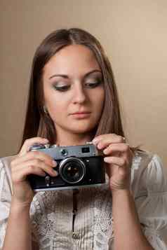 年轻的棕色（的）头发的女人美丽的衣服持有复古的相机