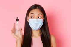 科维德流感大流行冠状病毒社会距离概念特写镜头可爱的愚蠢的漂亮的亚洲女孩医疗面具手洗手液建议防腐剂粉红色的背景