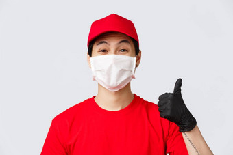 科维德self-quarantine在线购物交付概念快乐的亚洲快递医疗面具保护手套穿红色的统一的显示翘拇指批准推荐使安全订单