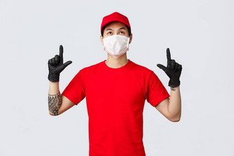 感兴趣可爱的亚洲交付的家伙纹身穿统一的帽红色的t恤指出手指前广告感兴趣阅读标志向上快递促进公司服务