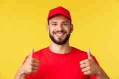 特写镜头友好的微笑交付的家伙红色的统一的帽t恤提供表达航运概念显示竖起大拇指批准推荐公司服务黄色的背景