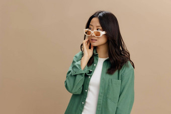 快乐享受朝鲜文年轻的女人<strong>卡其色</strong>绿<strong>色</strong>衬衫时尚的眼镜摆姿势孤立的米<strong>色</strong>柔和的工作室背景很酷的时尚提供太阳镜概念