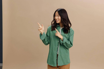 伟大的目的快乐的朝鲜文学生年轻的女人<strong>卡其色</strong>绿<strong>色</strong>衬衫点手指摆姿势孤立的米<strong>色</strong>柔和的工作室<strong>背景</strong>很酷的时尚提供生活方式情绪概念