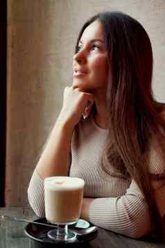 美丽的沉思的快乐女孩坐着咖啡馆圣诞节假期微笑做梦浅黑肤色的女人女人长头发饮料卡布奇诺咖啡咖啡拿铁窗口