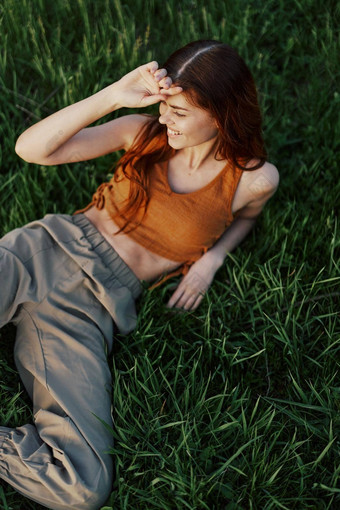年轻的女人长红色的头发微笑绿色草公园放松体育锻炼日落阳光