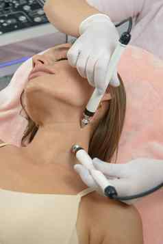美丽的女人水疗中心诊所接收刺激电面部治疗治疗师特写镜头女脸在临床上治疗