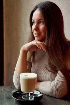 美丽的沉思的快乐女孩坐着咖啡馆圣诞节假期微笑做梦浅黑肤色的女人女人长头发饮料卡布奇诺咖啡咖啡拿铁窗口
