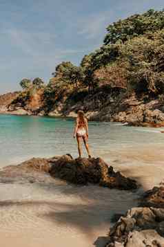 欧洲女人比基尼泳衣站向后石头岩石海洋海岸