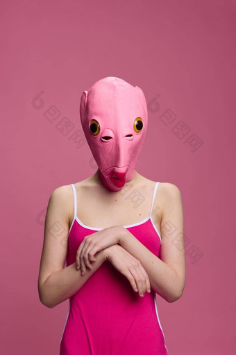 女人站粉红色的鱼面具头挑衅疯狂的万圣节粉红色的背景工作室