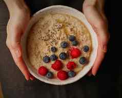 黑暗食物摄影板粥手黑暗背景前视图健康的早餐树莓蓝莓传讲种子枫木糖浆