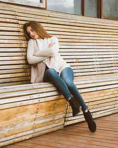 美丽的年轻的女孩长棕色（的）头发坐在木板凳上使木板休息睡觉打盹儿新鲜的空气户外照片拍摄有吸引力的女人冬天秋天