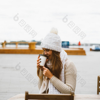美丽的年轻的女孩喝咖啡茶塑料杯子秋天冬天女人长头发<strong>温暖</strong>的衣服坐着海滨波罗的海海港口<strong>温暖</strong>热喝