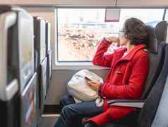 微笑女人红色的露营装备外套智能手机坐在窗口郊区火车旅行土地车辆