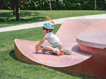 男孩下降了踢踏板车骑滑冰公园特殊的混凝土碗结构城市公园培训滑冰夏天