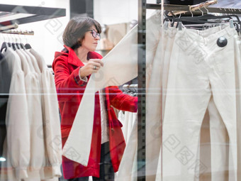 女人选择裤子服装商店<strong>休闲裤</strong>子挂衣架视图透明的商店窗口购物购物中心基本衣服日常穿现代城市时尚