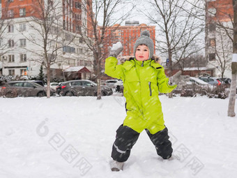 笑男孩绿色连身裤戏剧雪球雪院子里树休闲活动<strong>孩子</strong>们冬天