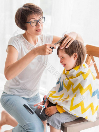 妈妈。削减儿子的头发男孩坐在覆盖布持有一对剪刀正常的情况下冠状病毒科维德检疫美首页生活方式