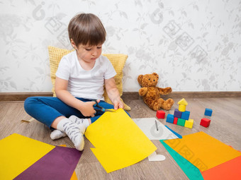 蹒跚学步的男孩学习减少彩色的纸剪刀孩子坐在地板上孩子们房间玩具块泰迪熊教育类孩子们发展中感觉感觉细电动机技能首页