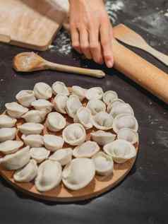 女人使水饺饺子传统的菜俄罗斯厨房使面团肉黑色的厨房表格面粉木餐具