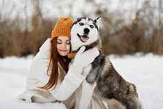 年轻的女人雪玩狗有趣的友谊生活方式