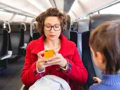 卷曲的女人红色的露营装备外套发短信智能手机郊区火车女人坐在儿子旅行土地车辆