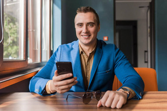 商人时尚的英俊的的家伙高加索人外观肖像西装衬衫花时间智能手机移动电话坐着表格咖啡馆