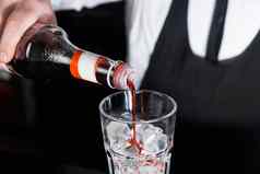 手专业酒保倒红色的糖浆玻璃冰多维数据集过程准备含酒精的鸡尾酒