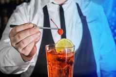 专业酒保把樱桃红色的冷冻含酒精的鸡尾酒酒吧镊子玻璃夜总会计数器