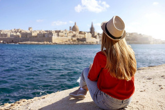 旅行概念独立的人享受户外休闲活动旅游热生活生活方式年轻的女人坐在边缘海令人惊异的景观瓦莱塔马耳他