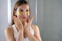美女孩应用金抗衰老黑眼圈面具镜子浴室皮肤护理女人补丁织物面具眼睛减少眼睛袋