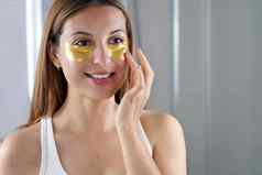 美女人应用金抗衰老黑眼圈面具镜子浴室皮肤护理女孩触摸补丁织物面具眼睛减少眼睛袋