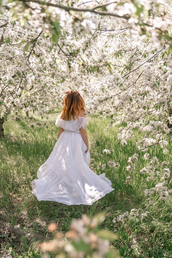 幻想女人长白色优雅的时尚长衣服走绿色春天开花樱桃花园快乐快乐的女孩公主新娘裙子织物苍蝇流动挥舞着风运动