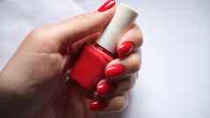女指甲持有瓶明亮的红色的指甲波兰的