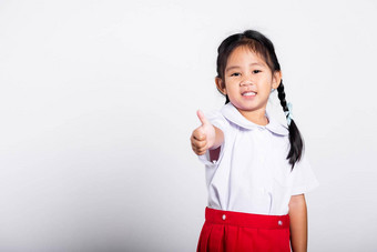 亚洲可爱的蹒跚学步的微笑快乐穿学生泰国统一的红色的裙子显示拇指手指
