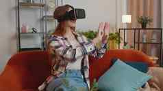 年轻的女孩虚拟现实耳机眼镜首页玩视频游戏使手势手