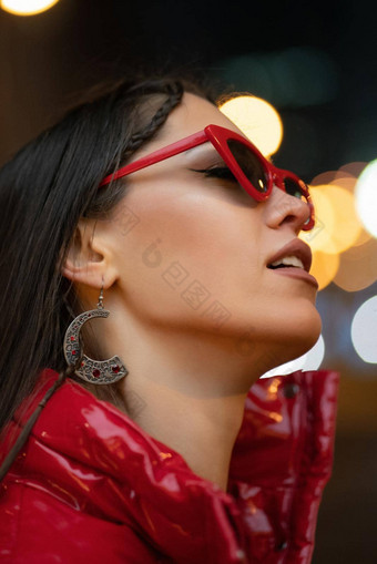 霓虹灯灯晚上生活时尚女孩太阳眼镜编织头发红色的光滑的外套站在户外晚上城市背景晚上生活概念晚上俱乐部生活概念