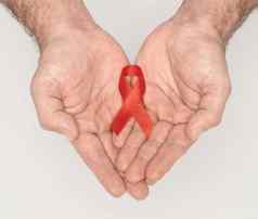 红色的意识丝带弓男人帮助手孤立的白色背景艾滋病毒艾滋病世界一天社会生活问题概念医疗保健医学概念艾滋病慈善机构基金概念